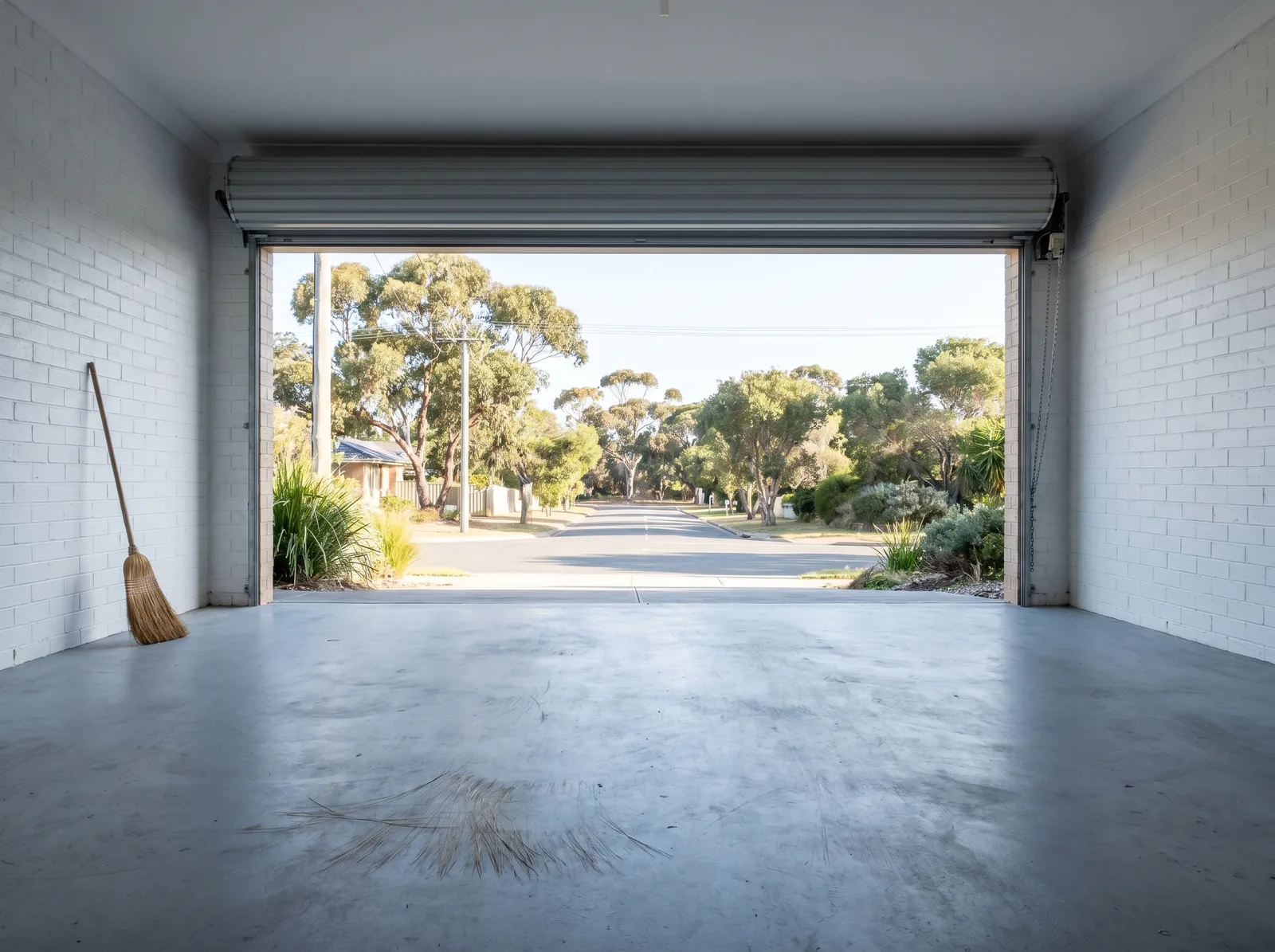 The same kind of garage empty and swept, roller door open to the street